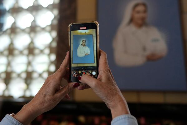 A believer takes a picture of a paint of Blessed Maria Carmen Rendiles at the Belen's school church where are their remains in Caracas, Venezuela, Monday, March 31, 2025. (AP Photo/Ariana Cubillos)