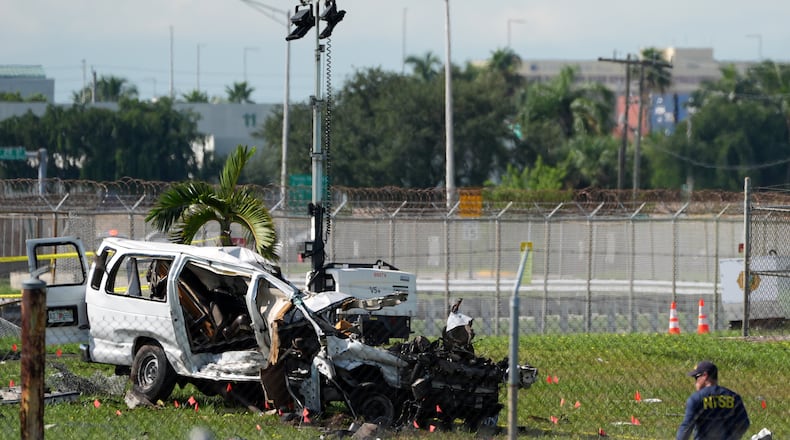 An NTSB investigator works near a damaged van at the site where an Amazon cargo plane overshot the runway two days earlier while landing at Miami International Airport, Tuesday, Sept. 8, 2026, in Miami. (AP Photo/Rebecca Blackwell)