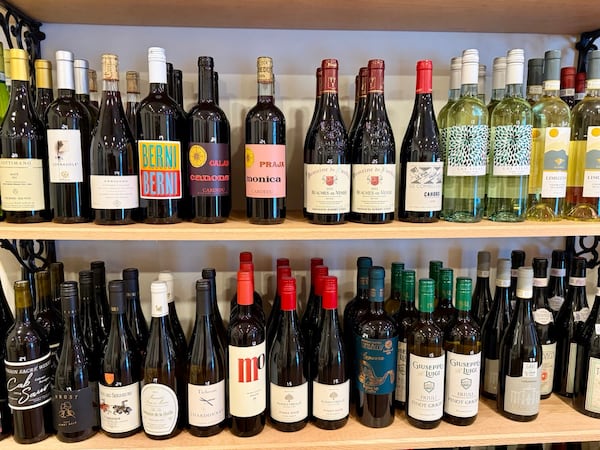 Two shelves full of wine bottles in a shop.