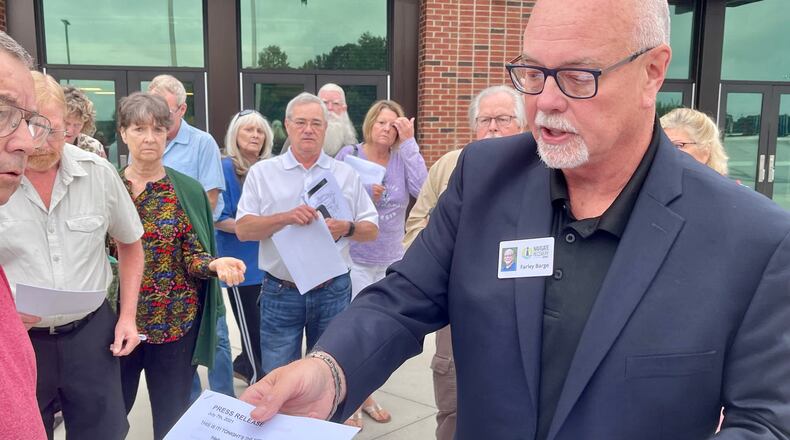 Farley Barge hands out flyers on Tuesday, July 20 after a Buford Planning Commissioners meeting to residents against proposed warehouse and office space on McEver Road. Barge runs an addiction recovery center for women next to the site of the proposed development. (Tyler Wilkins / tyler.wilkins@ajc.com)
