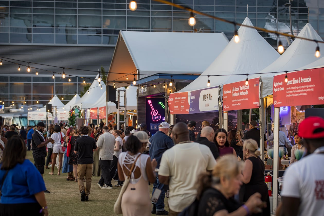 Crowds of people at dusk in front of tasting tents at the Atlanta Food & Wine Festival.