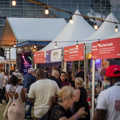 Crowds of people at dusk in front of tasting tents at the Atlanta Food & Wine Festival.