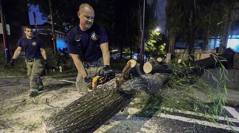Workers cut up a tree that fell Thursday morning at Williams and Spring streets in Downtown Atlanta.