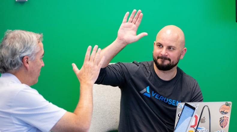 Paul Noble, the founder of Verusen, gets a high five from Jeff Wilson during an afternoon meeting at their Atlanta headquarters several years ago. The company markets AI-driven software used in making supply chains more efficient. STEVE SCHAEFER / SPECIAL TO THE AJC