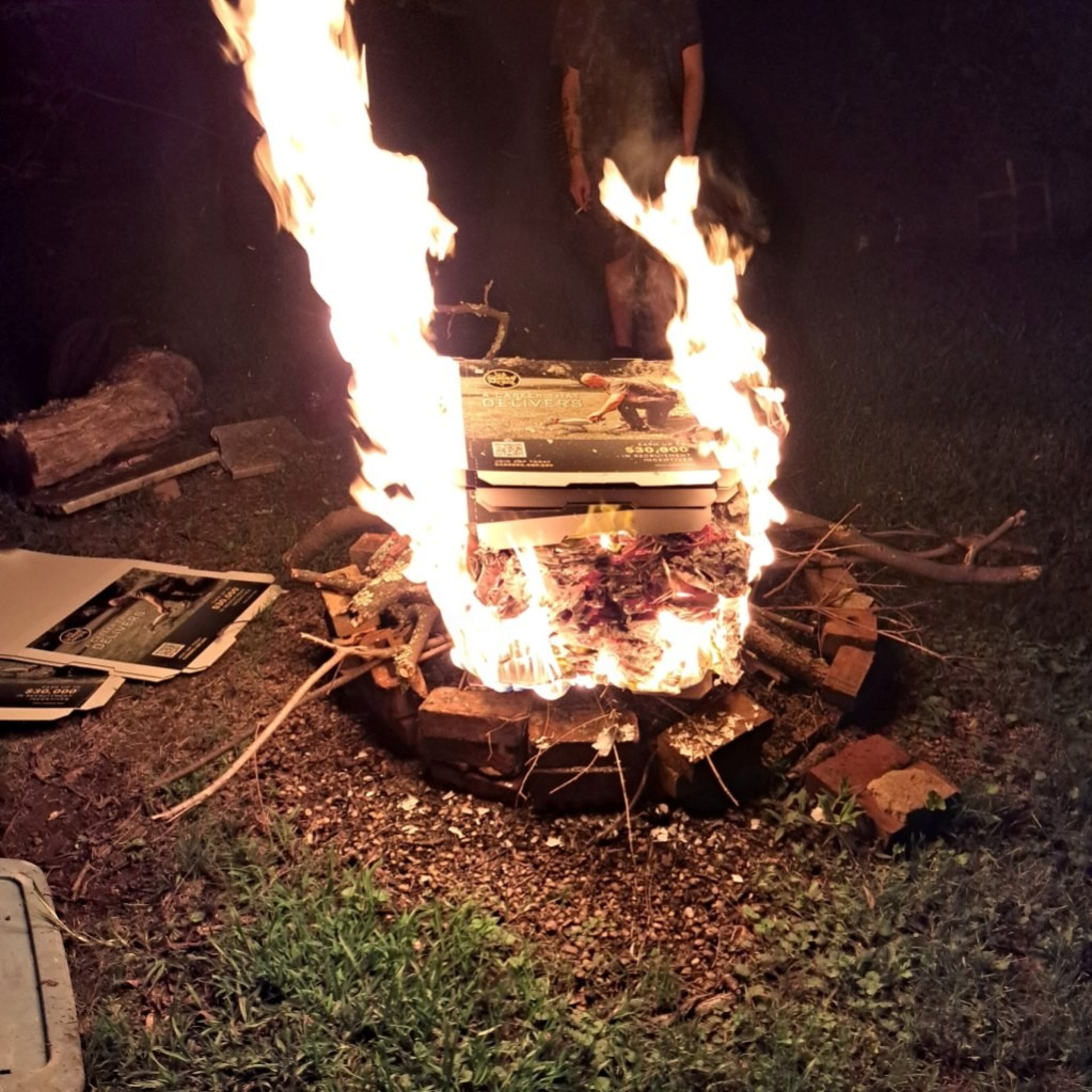 Pizza boxes with recruitment ads for U.S. Customs and Border Protection seen in a bonfire at a Mojo Pizza N' Pub employee's house on Wednesday, June 18, 2025. (Courtesy of April Adams)