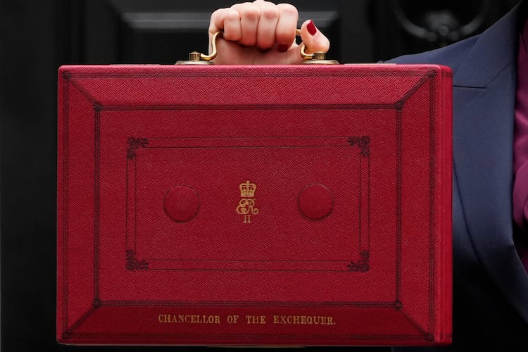 FILE - Britain's Chancellor of the Exchequer, Rachel Reeves, holds up the traditional red ministerial box containing her budget speech, as she poses for the media outside No 11 Downing Street, before departing to the House of Commons to deliver the budget in London, Wednesday, Oct. 30, 2024. (AP Photo/Kirsty Wigglesworth, File)