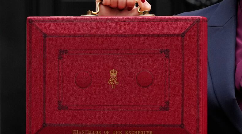 FILE - Britain's Chancellor of the Exchequer, Rachel Reeves, holds up the traditional red ministerial box containing her budget speech, as she poses for the media outside No 11 Downing Street, before departing to the House of Commons to deliver the budget in London, Wednesday, Oct. 30, 2024. (AP Photo/Kirsty Wigglesworth, File)