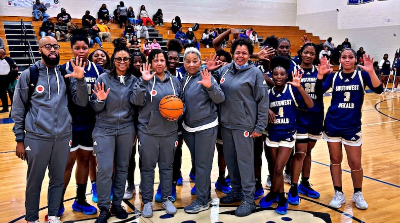 Kathy Walton (C with basketball) is surrounded by players and staff after earning her 500th victory on Feb. 6, 2024.