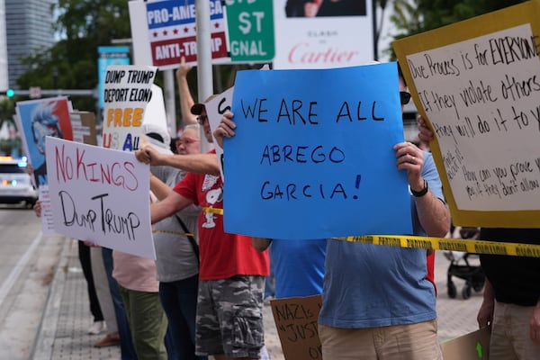FILE - People hold signs during a protest against the Trump administration, Saturday, April 19, 2025, in Miami. (AP Photo/Lynne Sladky, File)