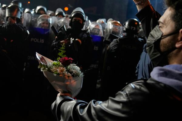 A protester offers flowers to riot police during a protest after Istanbul's Mayor Ekrem Imamoglu was arrested and sent to prison, in Istanbul, Turkey, Tuesday, March 25, 2025. (AP Photo/Khalil Hamra)