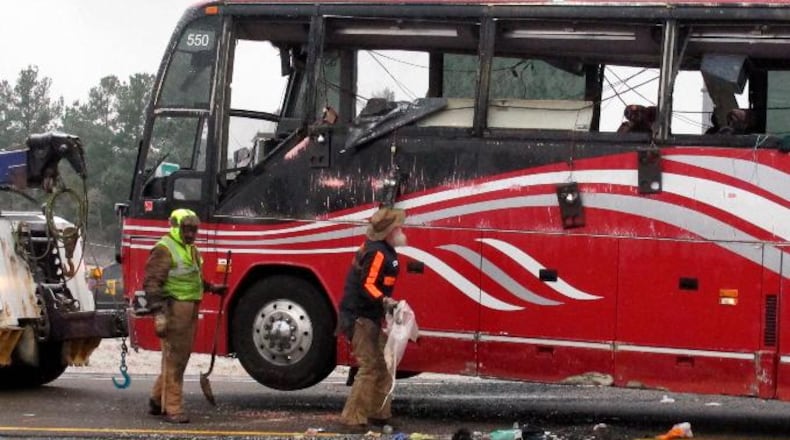 Workers clear debris from the scene of a bus crash that killed at least two people and injured dozens on Wednesday, Nov. 14, 2018, in Byhalia, Miss.