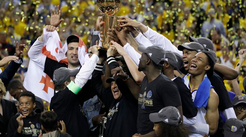 Golden State Warriors players, coaches and owners hold up the Larry O'Brien NBA Championship Trophy after Game 5 of basketball's NBA Finals between the Warriors and the Cleveland Cavaliers in Oakland, Calif., Monday, June 12, 2017. The Warriors won 129-120 to win the NBA championship. (AP Photo/Marcio Jose Sanchez)