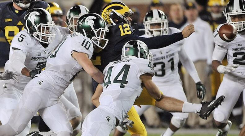 Michigan punter Blake O'Neill (12) fumbles a flubbed punt against Michigan State in the closing seconds of the second half of an NCAA college football game Saturday, Oct 17, 2015 in Ann Arbor, Mich. Michigan State's Jalen Watts-Jackson grabbed the flubbed punt and lumbered 38 yards into the end zone for a touchdown on the final play of the game, giving No. 7 Michigan State a shocking 27-23 win over No. 12 Michigan. (Dale G. Young/Detroit News via AP) DETROIT FREE PRESS OUT; HUFFINGTON POST OUT; MANDATORY CREDIT