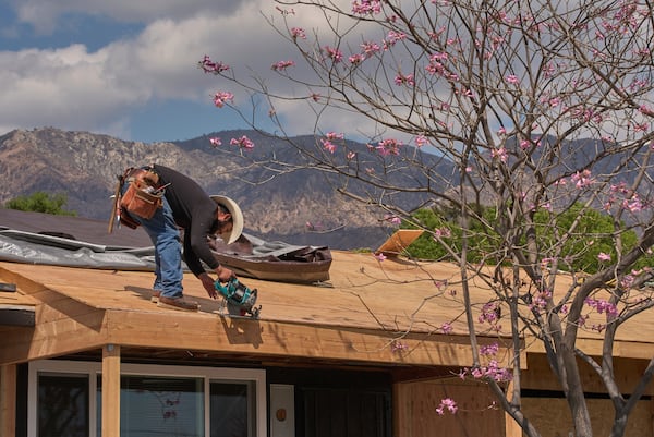A construction worker installs a new roof on a fire damaged home in Altadena, Calif., on Friday, April 4, 2025. (AP Photo/Damian Dovarganes)