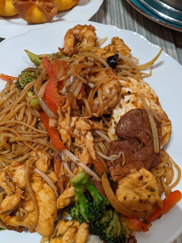 A close-up shot of a plate of hand-pulled stir-fried noodles with meat and vegetables.