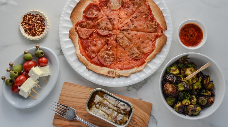 Take resolutions to reality with healthy snacks like (clockwise from bottom left) toothpick skewers of olive, tomato and feta; tortilla pizza; roasted Brussels sprouts; and tinned seafood. (Virginia Willis for The Atlanta Journal-Constitution)