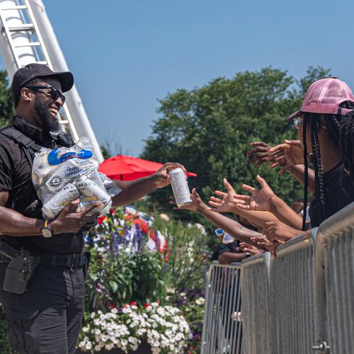 Children reach for cold bottles of water from U.S. National Park Police Officer R. Douglass as they wait in line for the ferris wheel at the Great American State Fair on the National Mall, Wednesday, July 1, 2026, in Washington. (AP Photo/Jen Golbeck)