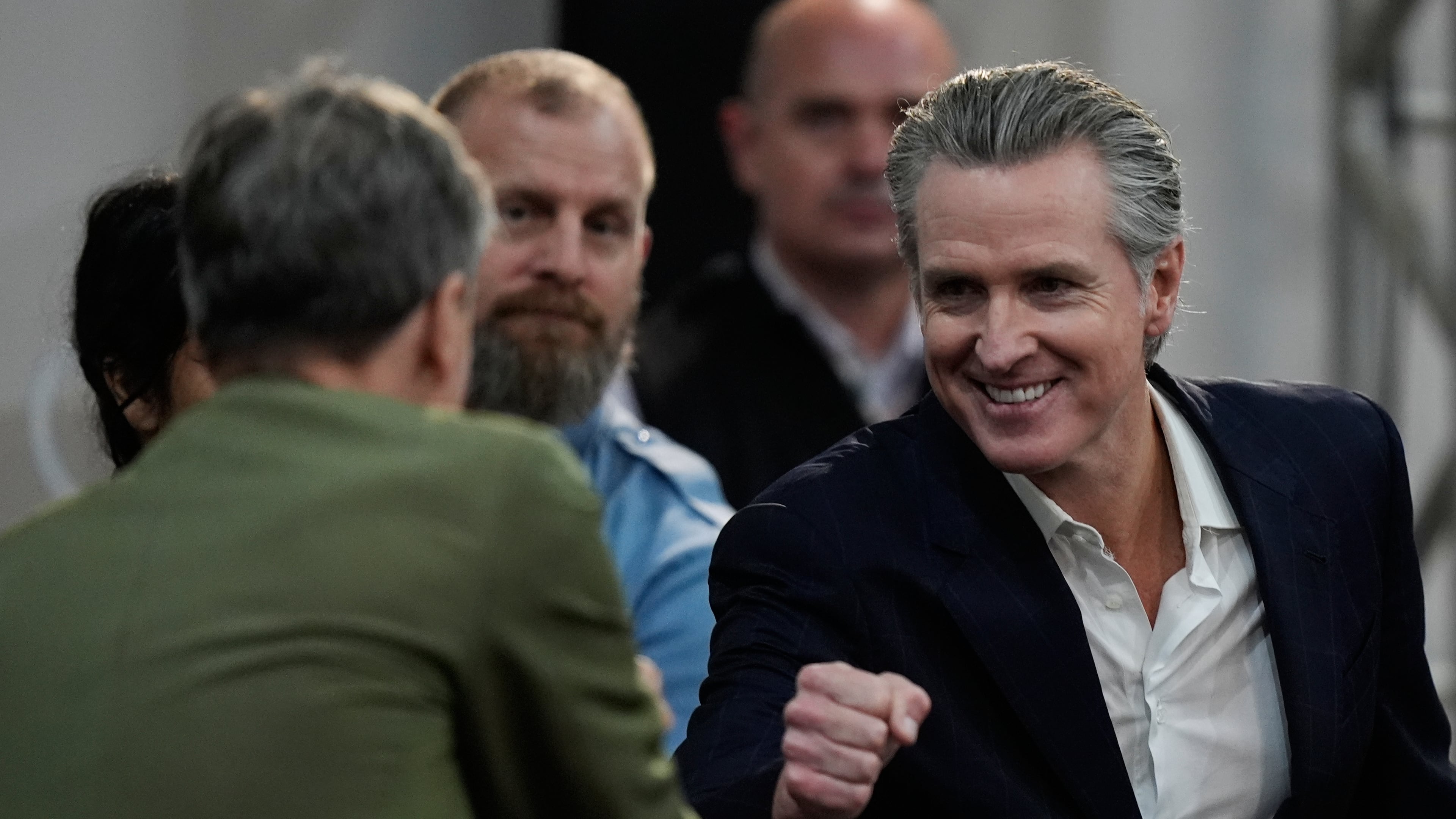 California Gov. Gavin Newsom, right, greets people as he arrives for a news conference at the COP30 U.N. Climate Summit, Tuesday, Nov. 11, 2025, in Belem, Brazil. (AP Photo/Fernando Llano)