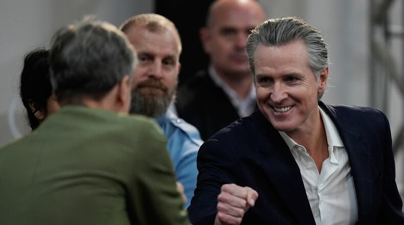 California Gov. Gavin Newsom, right, greets people as he arrives for a news conference at the COP30 U.N. Climate Summit, Tuesday, Nov. 11, 2025, in Belem, Brazil. (AP Photo/Fernando Llano)