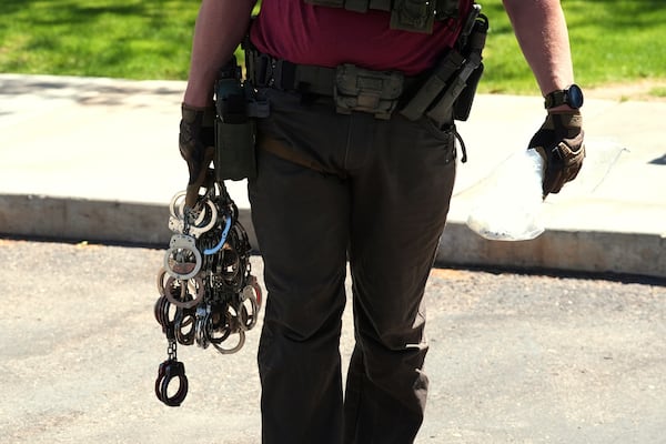 A federal agent holds handcuffs outside an immigration court, Wednesday, May 21, 2025, in Phoenix. (AP Photo/Ross D. Franklin)