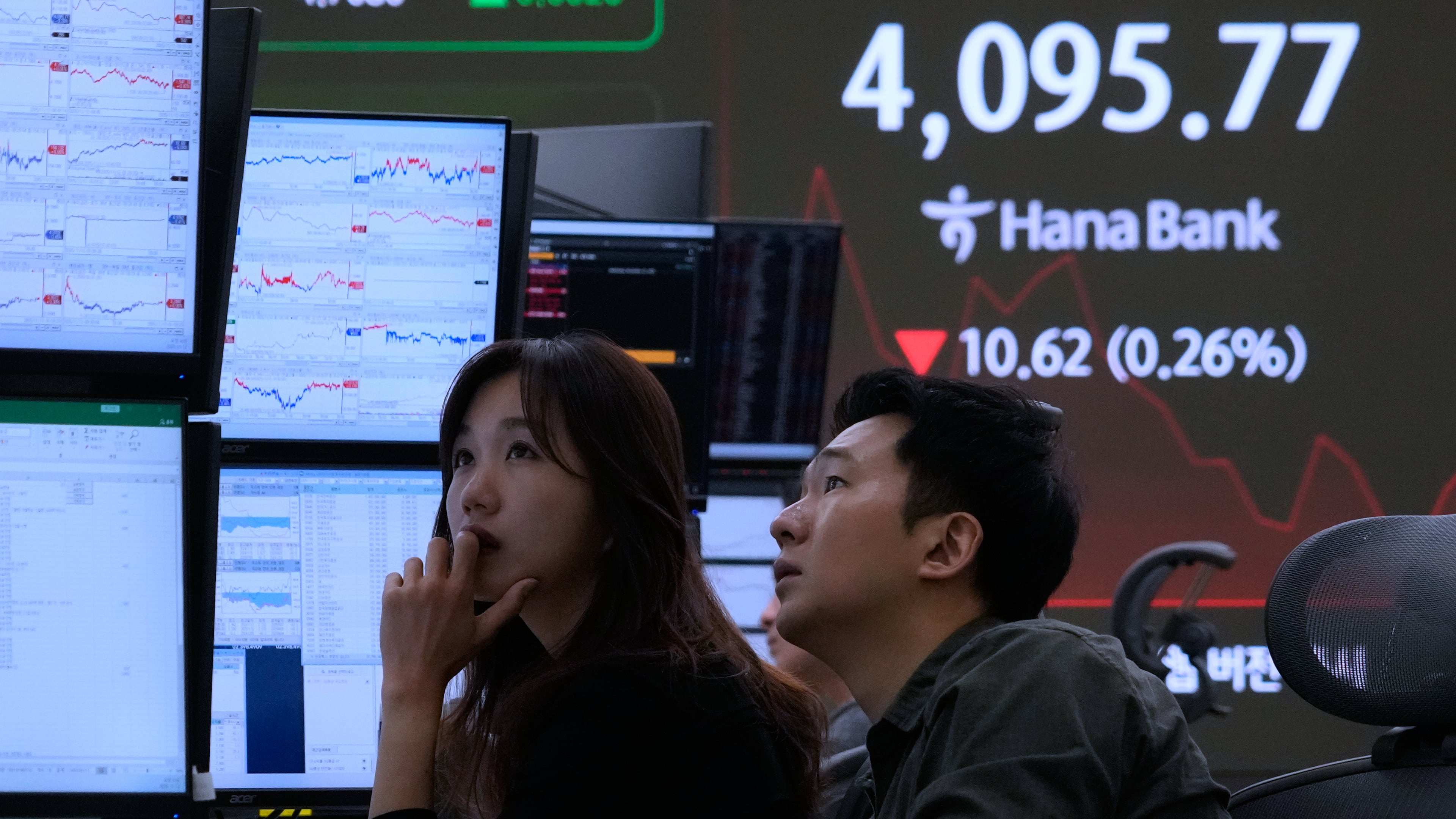 Currency traders watch monitors near a screen showing the Korea Composite Stock Price Index (KOSPI) at the foreign exchange dealing room of the Hana Bank headquarters in Seoul, South Korea, Wednesday, Nov. 12, 2025. (AP Photo/Ahn Young-joon)