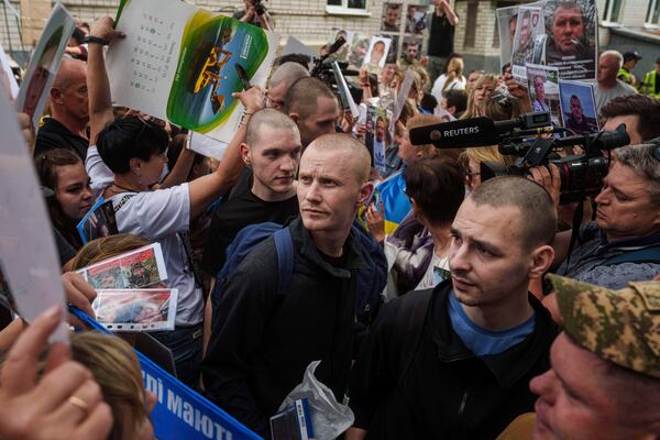 Ukrainian soldiers walk though human corridor with people holding photos of their missed relatives after returning from captivity after a POWs exchange between Russia and Ukraine, in Chernyhiv region, Ukraine, Monday, June 9, 2025. (AP Photo/Evgeniy Maloletka)