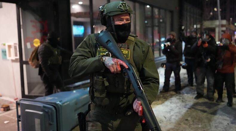 A federal agent stands guard near a hotel during a noise demonstration protest in response to federal immigration enforcement operations in the city Sunday, Jan. 25, 2026, in Minneapolis. (AP Photo/Adam Gray)
