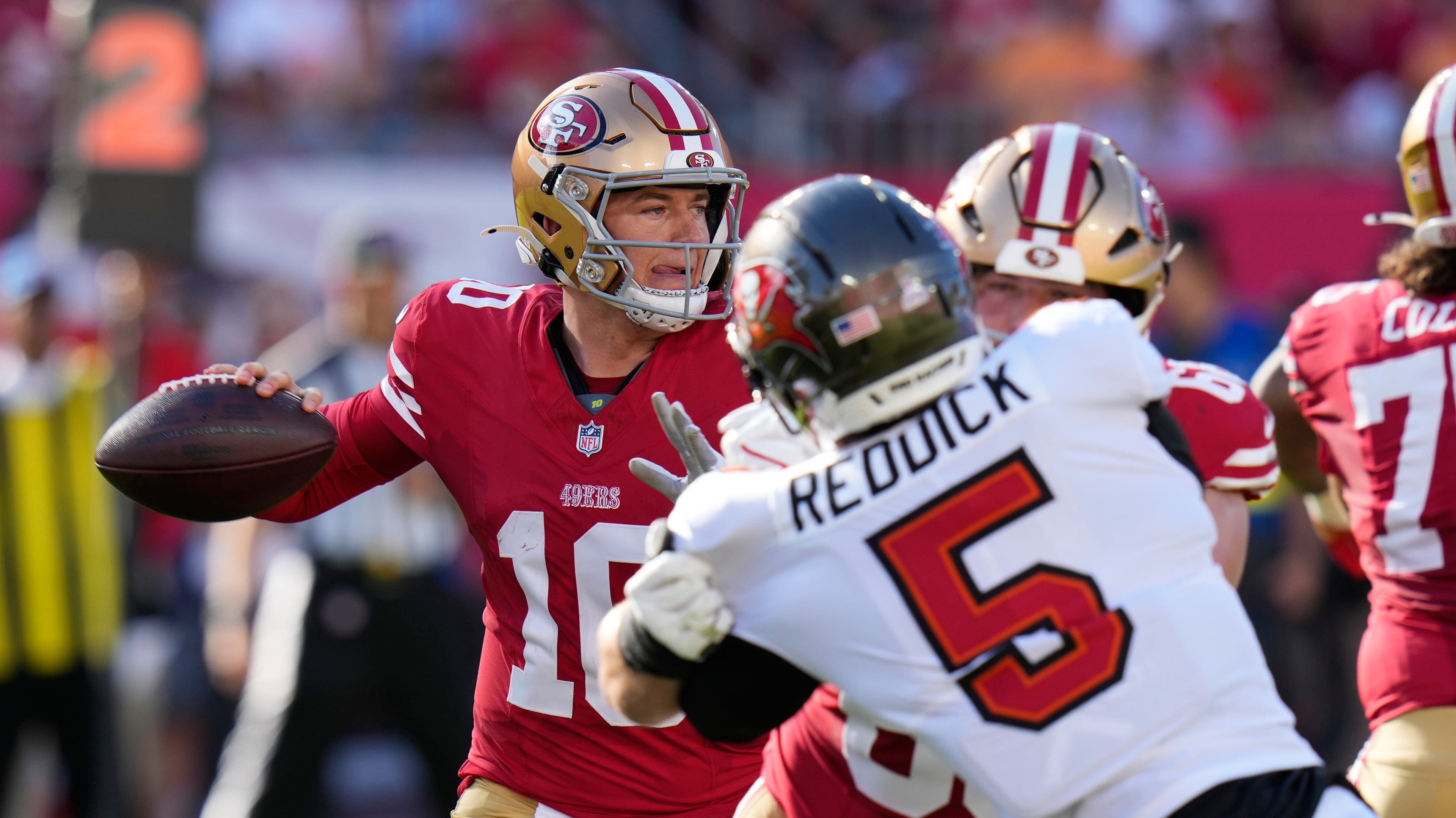 San Francisco 49ers quarterback Mac Jones, left, passes as Tampa Bay Buccaneers outside linebacker Haason Reddick applies pressure during the first half of an NFL football game in Tampa, Fla., Sunday, Oct. 12, 2025. (Chris O'Meara/AP)