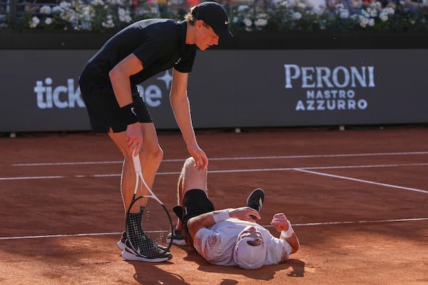 Italy's Jannik Sinner, standing, tends to Netherlands' Jesper De Jong who lies on the court after falling, during their tennis match at the Italian Open at the Foro Italico, in Rome, Monday, May 12, 2025. (AP Photo/Alessandra Tarantino)