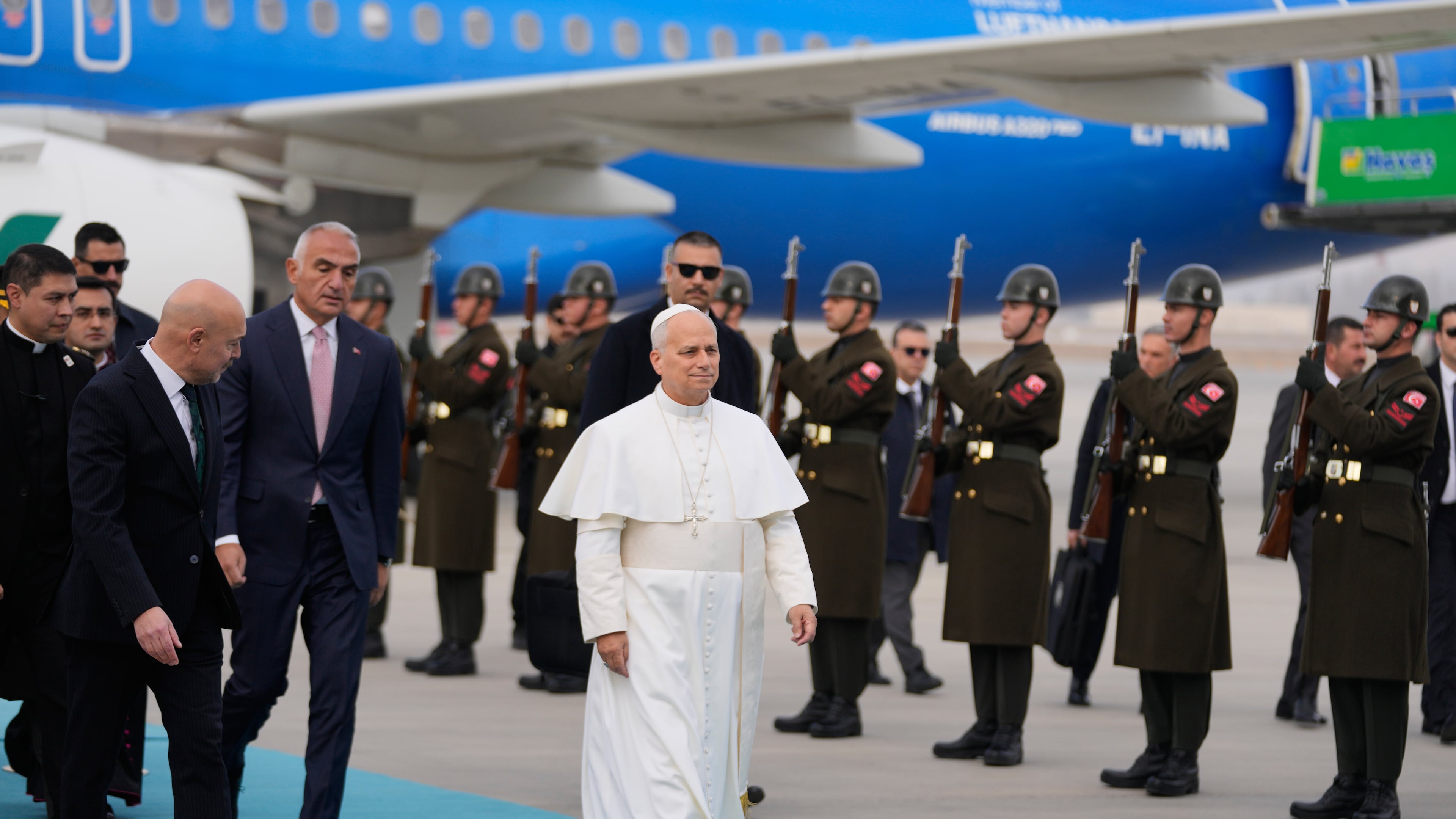 Pope Leo XIV walks as he is welcomed upon his arrival at Esenboga International Airport in Ankara, Turkey, Thursday, Nov. 27, 2025, marking the beginning of his first foreign trip. (AP Photo/Khalil Hamra)