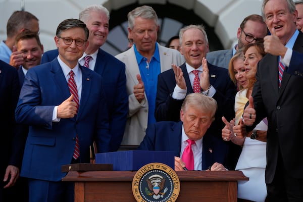 President Donald Trump, surrounded by members of Congress, signs his signature bill of tax breaks and spending cuts at the White House on Friday, July 4, 2025, in Washington. (Julia Demaree Nikhinson/AP)