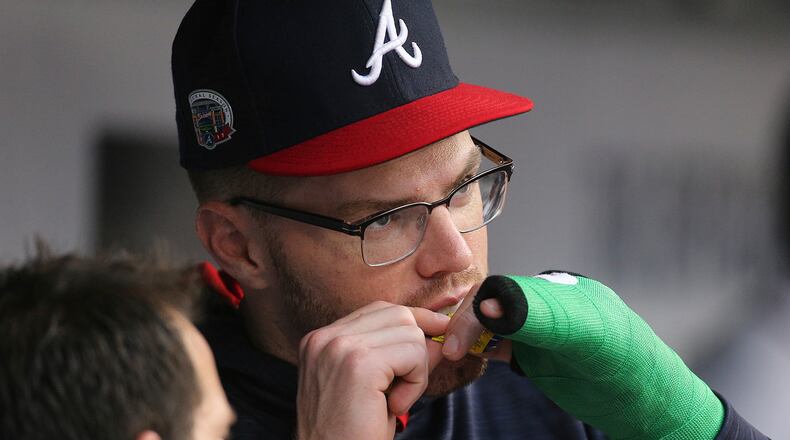 Atlanta Braves first baseman Freddie Freeman, whose wrist was broken Wednesday by a pitch from Toronto Blue Jays' Aaron Loop and is in a cast, opens a piece of bubble gum in the dugout during the first inning of the teams' baseball game Thursday, May 18, 2017, in Atlanta. (Curtis Compton/Atlanta Journal-Constitution via AP)