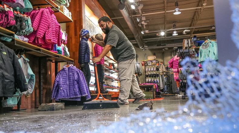 Employees clean up The North Face store on West Paces Ferry Road after a smash-and-grab burglary. JOHN SPINK / JSPINK@AJC.COM