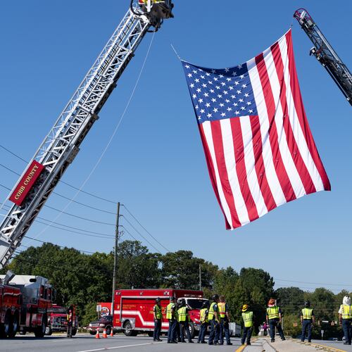 The Cobb County fire department hangs a U.S. flag from their fire trucks as a procession for fallen Dekalb County Firefighter Preston Fant arrives at West Cobb Funeral Home on Wednesday, Sept. 10, 2025. (Ben Hendren for the AJC)