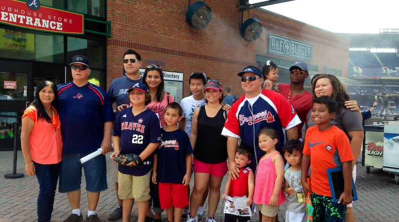 Joe Raymond (on the right with Braves jersey, cap and sunglasses) poses with about 18 of his family members before Sunday’s Hall of Fame induction screening at Turner Field. (Erica A. Hernandez/ehernandez@ajc.com)