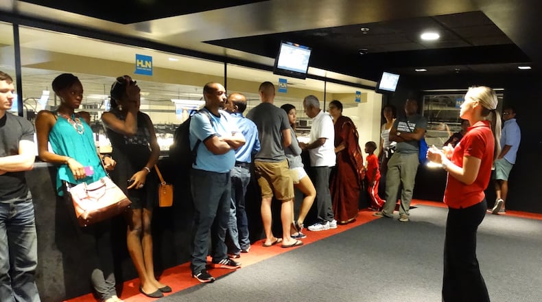CNN Inside Studio Tour guide Lindsay Walker (right) gives tourists statistics in a space overlooking HLN’s newsroom. (Rodney Ho / rho@ajc.com)