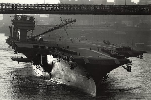 This 1961 image provided by Cornell University/Herbert F. Johnson Museum of Art shows the U.S.S. Constellation aircraft carrier passing under the Brooklyn Bridge in New York. The ships had to be designed to be able to lower their masts to pass under the bridge to avoid striking it. (Cornell University/Herbert F. Johnson Museum of Art via AP)