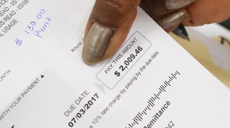 Toby Jennings of Lithonia holds her water bill of $2009.49 while DeKalb CEO Mike Thurmond updated residents about the depth of the county's remaining water billing problems during his third public update on June 29.  Curtis Compton/ccompton@ajc.com