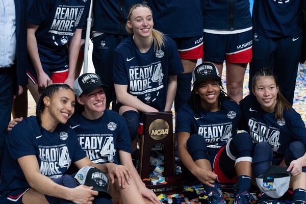 UConn players from left, Azzi Fudd, Ashlynn Shade, Paige Bueckers, KK Arnold and Kaitlyn Chen pose with the trophy after a game against Southern California in the Elite Eight of the NCAA college basketball tournament Monday, March 31, 2025, in Spokane, Wash. (AP Photo/Jenny Kane)