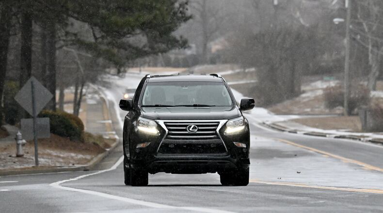 A car travels along as light snow falls in Snellville on Saturday, Jan. 31, 2026. Snow has been steadily turning parts of Middle and North Georgia, including metro Atlanta, into a snow globe. (Hyosub Shin/AJC)