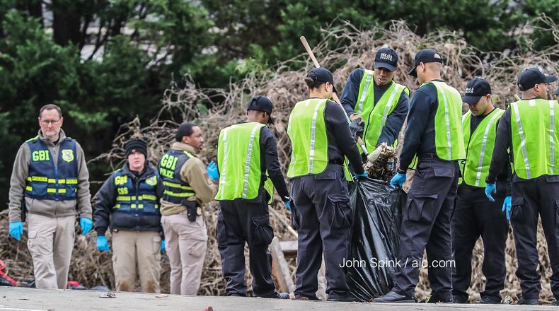 GBI agents search diligently through the brush on Candler Road on Wednesday after an officer-involved shooting Tuesday night, blocks away from a December shooting that killed another DeKalb officer.