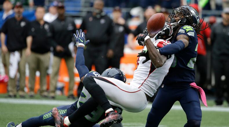 Seattle Seahawks cornerback Richard Sherman, right, and Earl Thomas (obscured) break up a pass intended for Atlanta Falcons wide receiver Julio Jones (11) in the second half of an NFL football game, Sunday, Oct. 16, 2016, in Seattle. The Seahawks beat the Falcons 26-24. (AP Photo/Elaine Thompson)