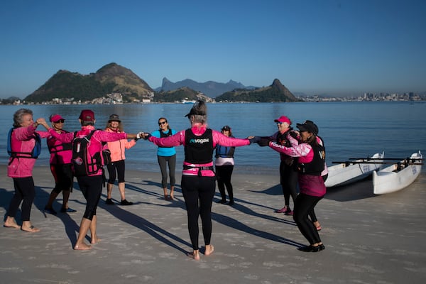 The Rosas Va'a Hawaiian canoeing team, whose members are women who have undergone cancer treatment, gather after training on the water, at Charitas Beach in Niteroi, Rio de Janeiro state, Thursday, June 26, 2025. (AP Photo/Bruna Prado)