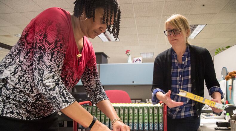 Virginia Collier, right, manager of collections management and technical services at Atlanta Central library, and Charmaine Johnson, assistant manager of collections management and technical services, prepare a leased Walter Mosley novel for distribution at Atlanta Central Library. ALYSSA POINTER/ALYSSA.POINTER@AJC.COM