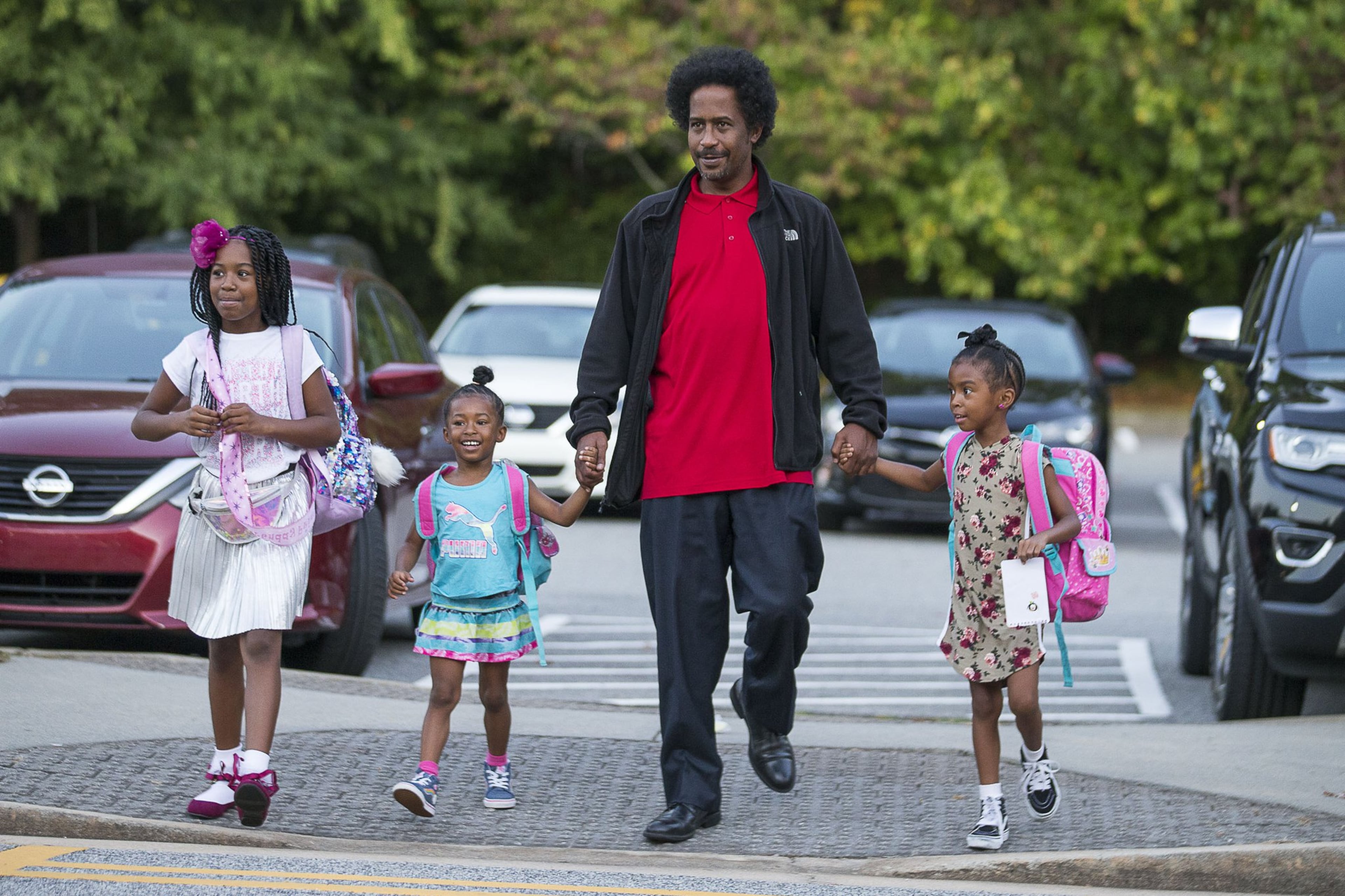 William White IV walks his daughters Allison White (from left), Amber White (second from left) and Ashley White (right) to M. Agnes Jones Elementary School on Friday during the national Million Fathers March Day in Atlanta’s Ashview Heights neighborhood. Fathers Incorporated, a local nonprofit, helped with welcoming the students and dads to the school. ALYSSA POINTER / ALYSSA.POINTER@AJC.COM