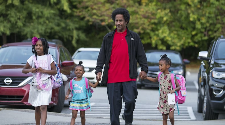 William White IV walks his daughters Allison White (from left), Amber White (second from left) and Ashley White (right) to M. Agnes Jones Elementary School on Friday during the national Million Fathers March Day in Atlanta’s Ashview Heights neighborhood. Fathers Incorporated, a local nonprofit, helped with welcoming the students and dads to the school. ALYSSA POINTER / ALYSSA.POINTER@AJC.COM