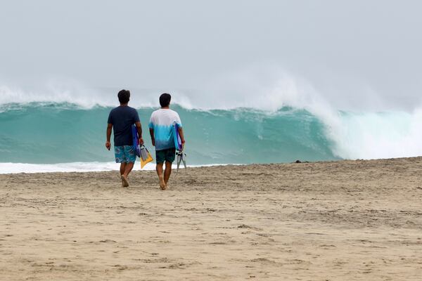 People walk on Zicatela beach prior to the arrival of Hurricane Erick in Puerto Escondido, Oaxaca state, Mexico, Wednesday, June 18, 2025. (AP Photo/Luis Alberto Cruz)