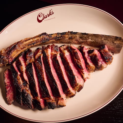 A large, bone-in steak is cut into slices for service.