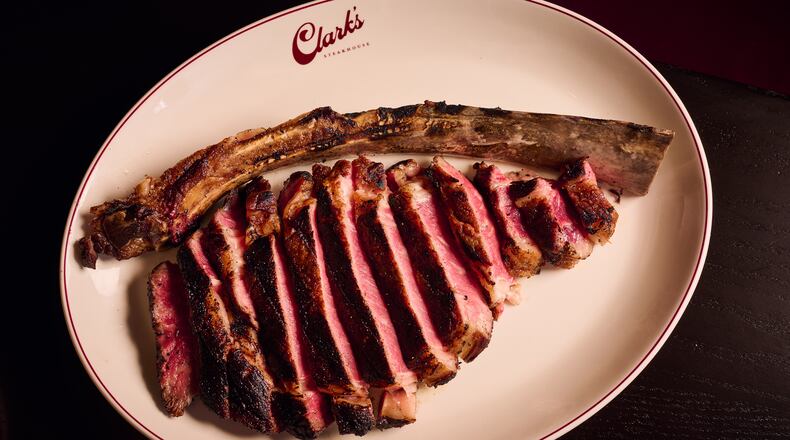 A large, bone-in steak is cut into slices for service.