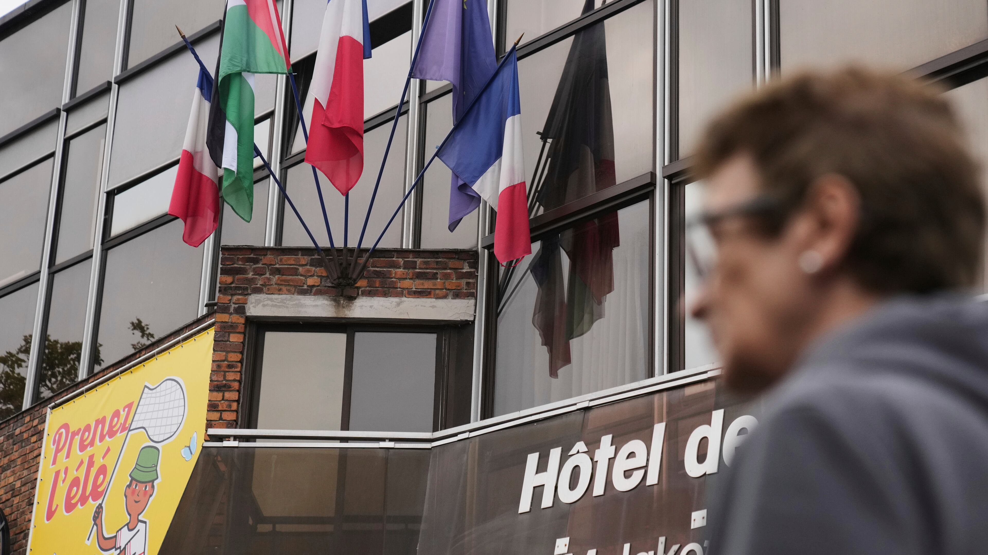 A woman walks past a Palestinian flag set up between French and European flags at the Malakoff's town hall, outside Paris, as France prepares to formally recognize a Palestinian state at the United Nations General Assembly, Sunday, Sept. 21, 2025.(AP Photo/Christophe Ena)